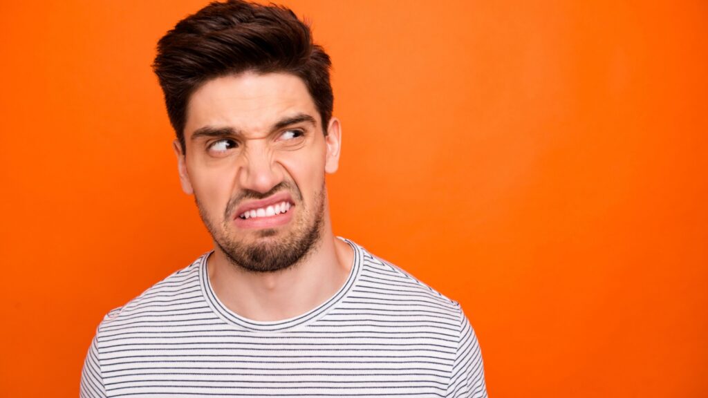 Ugh! I won't eat this! Closeup photo of disgusted guy look side empty space negative reacting wear casual striped t-shirt isolated bright orange color background