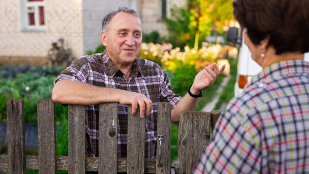 neighbors middle aged man and woman chatting near the fence in the village