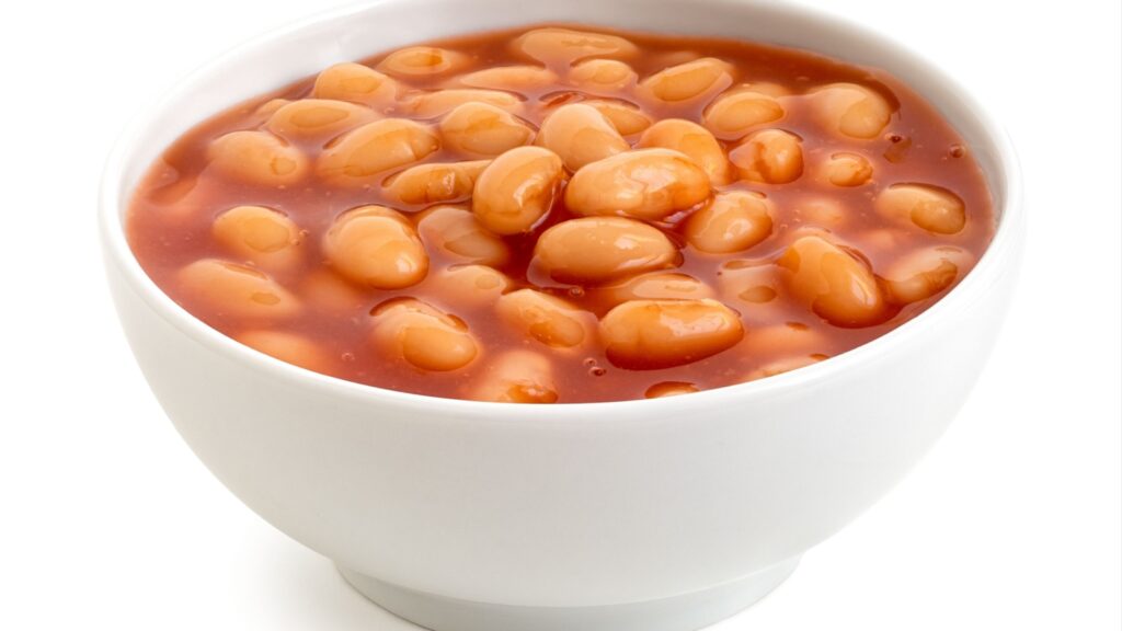 Baked beans in tomato sauce in a white ceramic bowl isolated on white.