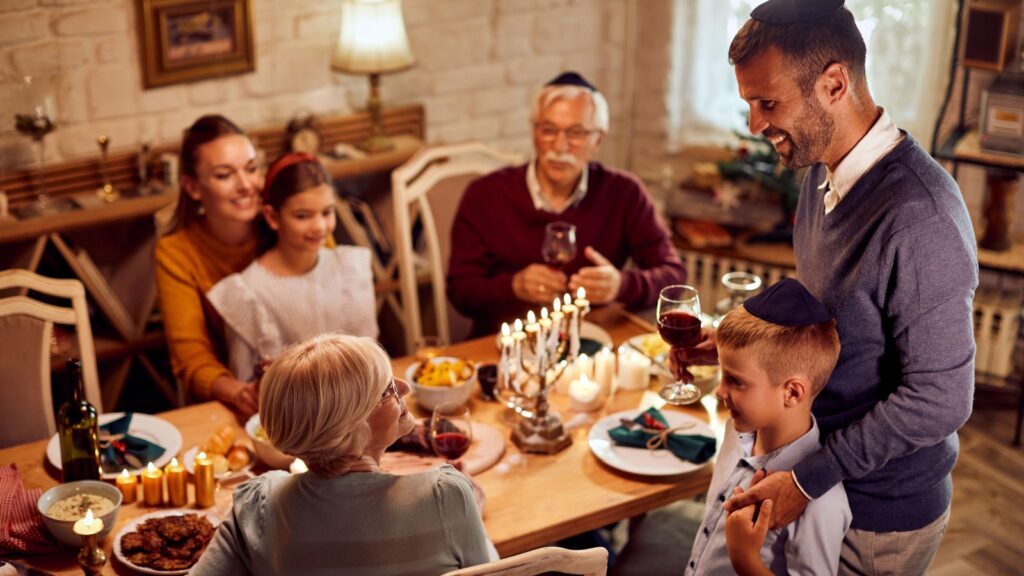 Happy multi-generation family enjoying in traditional Hanukkah meal at dining table.