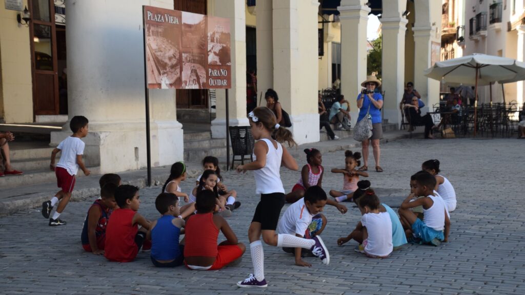 Havana, Cuba May 2 2016: unidentified Cuban kids children playing games outside in front of building in town square in Havana, Cuba with unidentified people in background