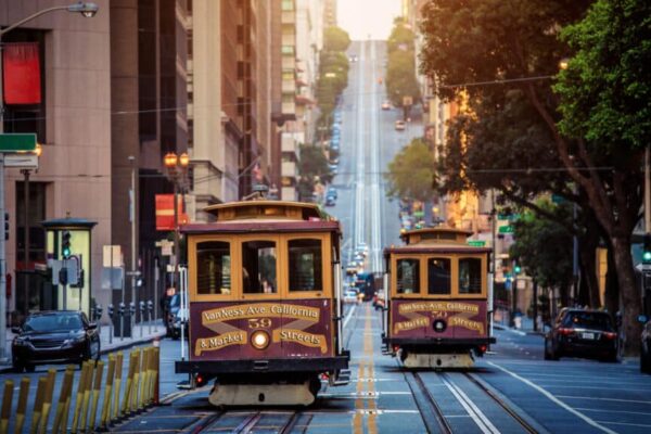 Classic view of historic traditional Cable Cars riding on famous California Street in morning light at sunrise with retro vintage style cross processing filter effect, San Francisco, California, USA