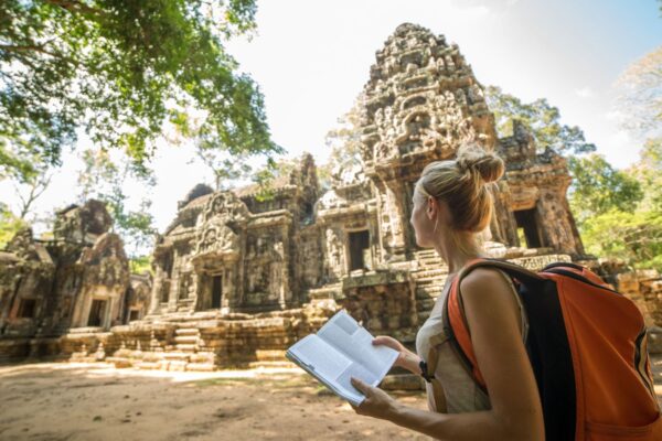 A woman holding an open book looking at an ancient structure