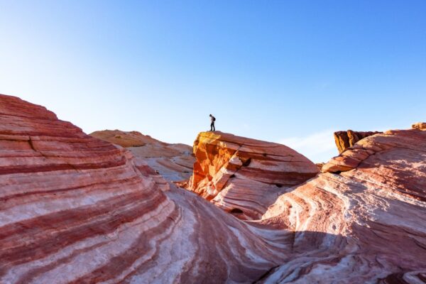 A hiker enjoys the desert views from atop the colorful Fire Wave in Valley of Fire State Park, Nevada.