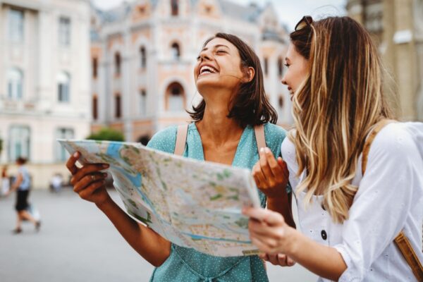 Fun, friends, travel and tourism concept. Beautiful girls looking for direction in the city