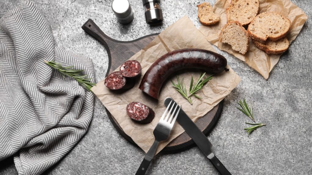Tasty blood sausage with rosemary on grey table, flat lay