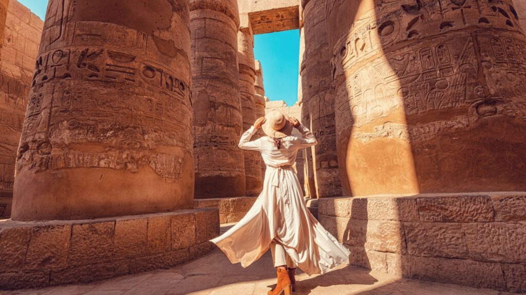 Woman traveler explores the ruins of the ancient Karnak temple in the city of Luxor in Egypt. Great row of columns with carved hieroglyph