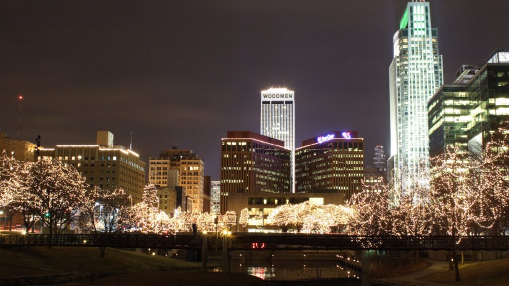 Omaha Trees lit up in white Lights in the city with reflection in the water.