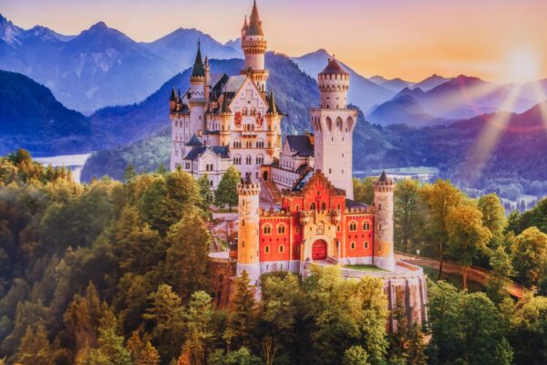 Bavaria, Germany - July 10, 2023 - A stunning view of Neuschwanstein Castle at sunrise, surrounded by lush forests and the Bavarian Alps in the background, Bavaria region.