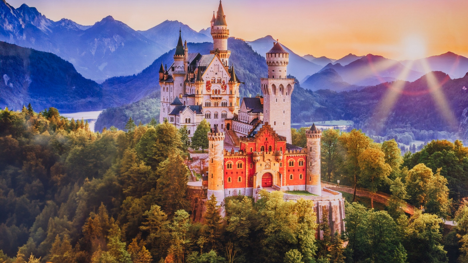 Bavaria, Germany - July 10, 2023 - A stunning view of Neuschwanstein Castle at sunrise, surrounded by lush forests and the Bavarian Alps in the background, Bavaria region.