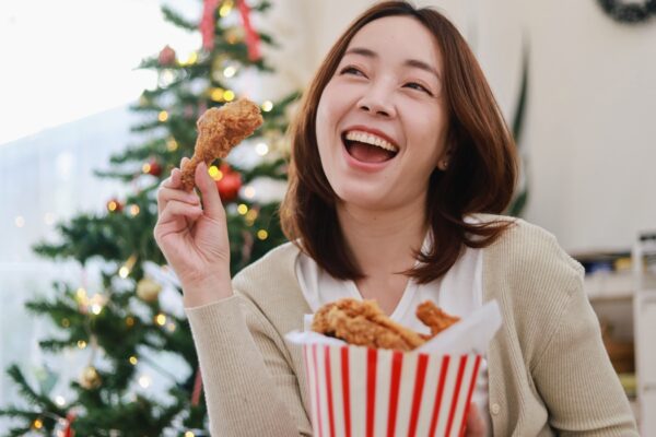 Beautiful Asian woman eating a crispy fried chicken in bucket