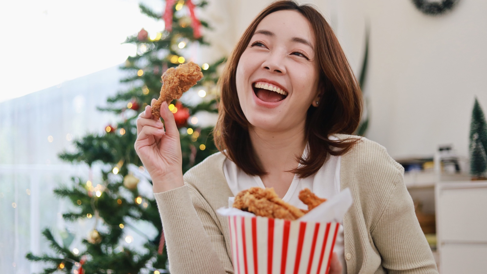 Beautiful Asian woman eating a crispy fried chicken in bucket