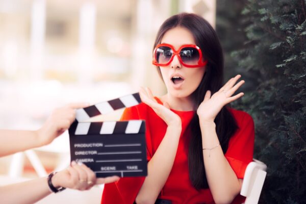 Surprised Actress with Oversized Sunglasses Shooting Movie Scene - Diva in red dress and big shades starring in an artistic film
