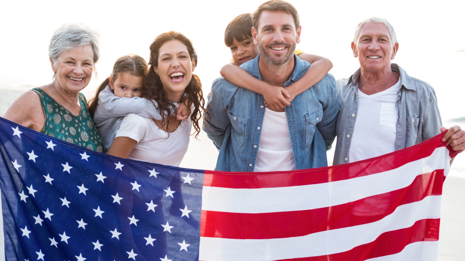 Happy family with an american flag at the beach