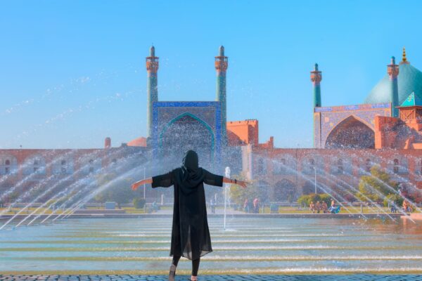 Beautiful Iranian girl wearing abaya with arms up happy - Shah (Imam) Mosque (Jameh Abbasi Mosque), Imam mosque in Naghsh-i Jahan Square - Isfahan, Iran,