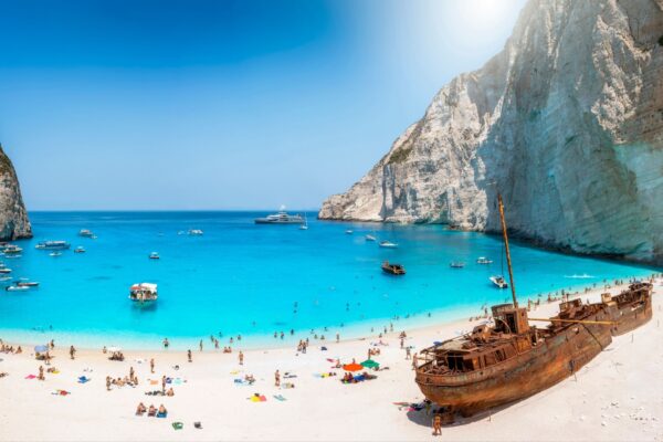 Panoramic view of the famous Navagio shipwreck beach on Zakynthos island, Greece, with people enjoying the light blue colored sea