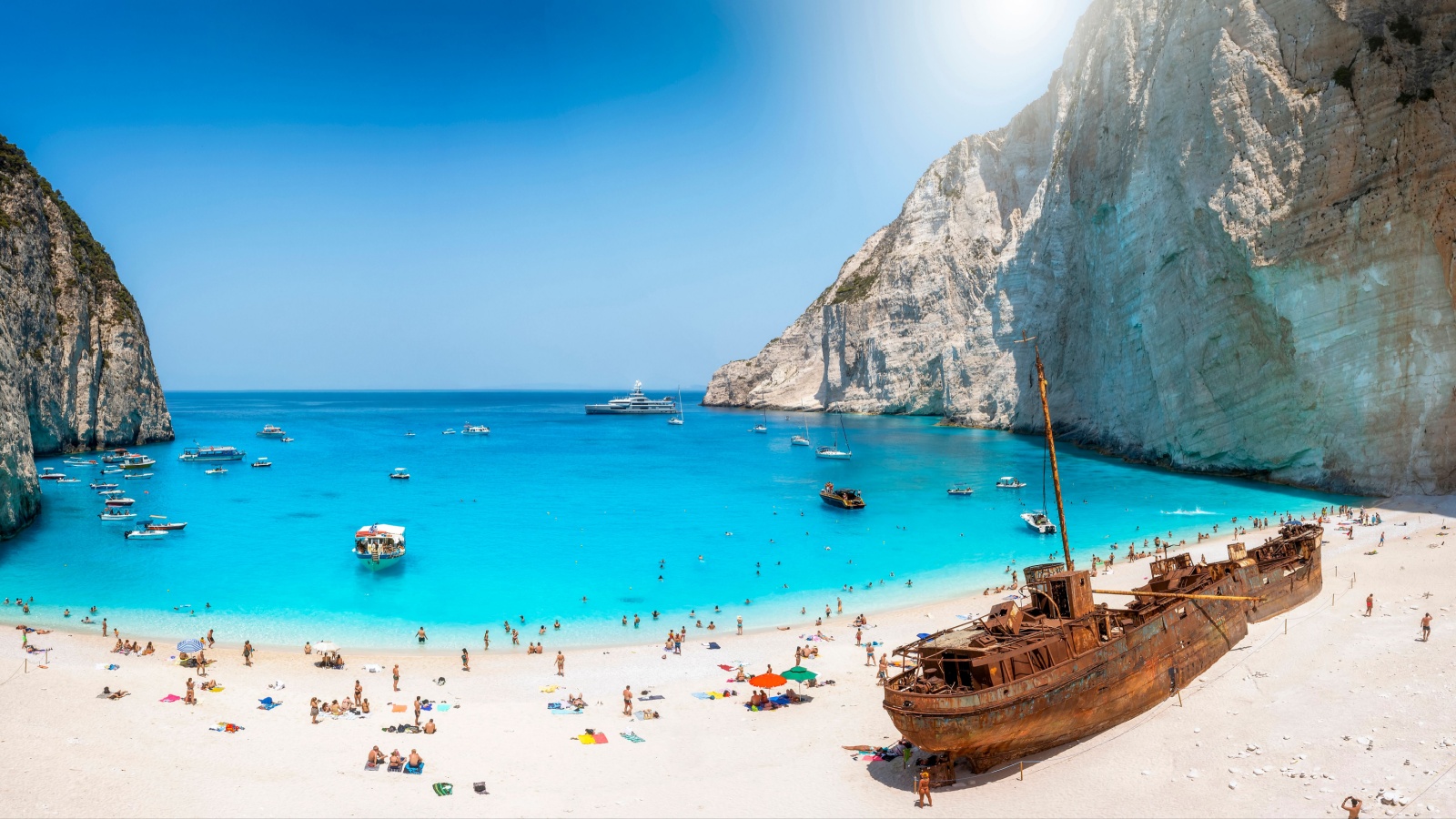 Panoramic view of the famous Navagio shipwreck beach on Zakynthos island, Greece, with people enjoying the light blue colored sea