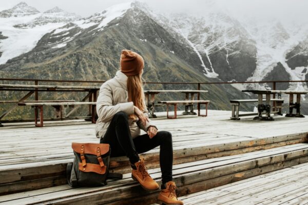 Girl traveler with backpack enjoy mountain nature sitting on wooden bridge. Cheget, Kabardino-Balkaria, Russia.