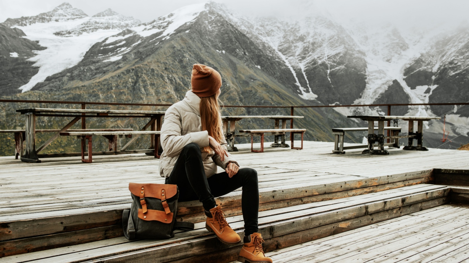 Girl traveler with backpack enjoy mountain nature sitting on wooden bridge. Cheget, Kabardino-Balkaria, Russia.