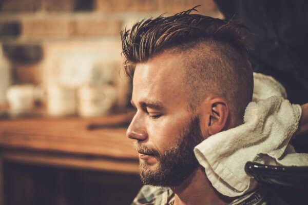 Hairstylist washing client's hair in barber shop