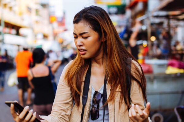 Asian woman traveler annoyed with message in mobile