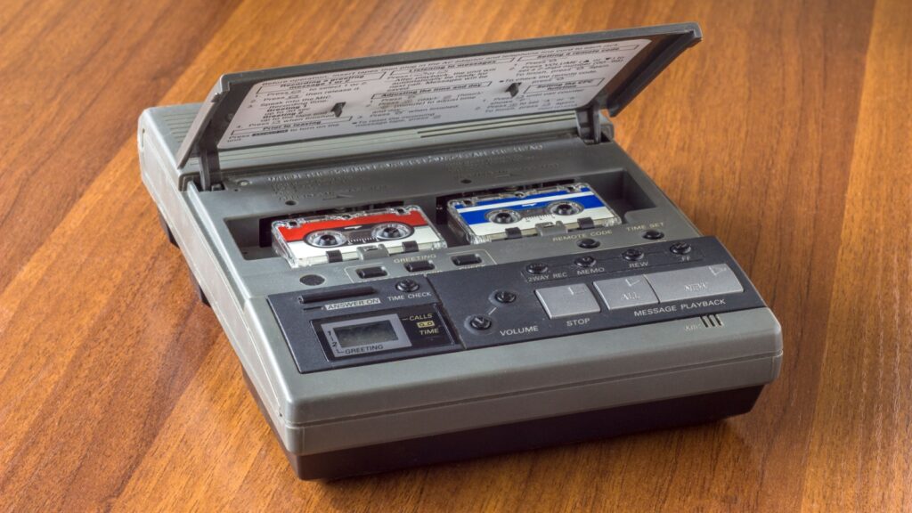 old vintage answering machine with two small tape cassettes on a wooden table surface