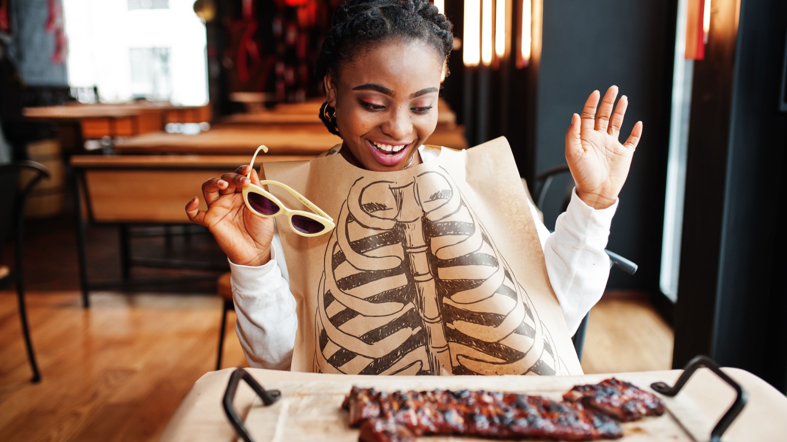 African woman eat spicy hot grilled spare ribs on wooden desk.