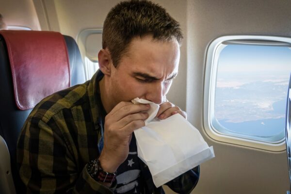 Nausea during the flight. A young guy gets carsick in transport. Nervous young man with aviophobia breathing into paper bag in airplane