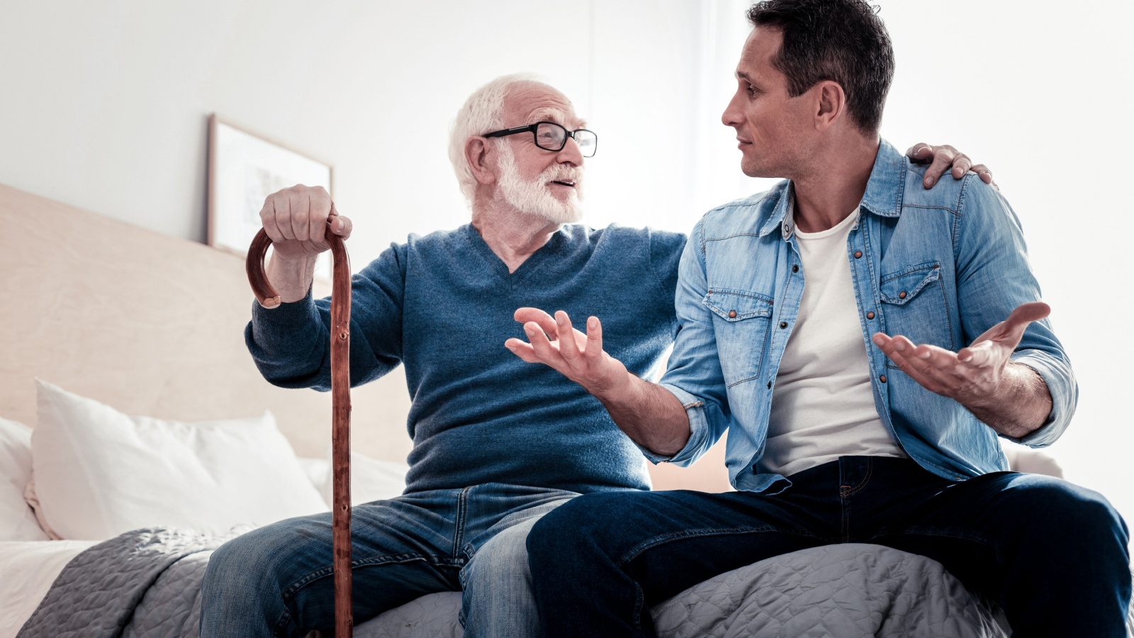 Pleasant communication. Pleasant nice elderly man looking at his grandson and holding his shoulder while talking to him