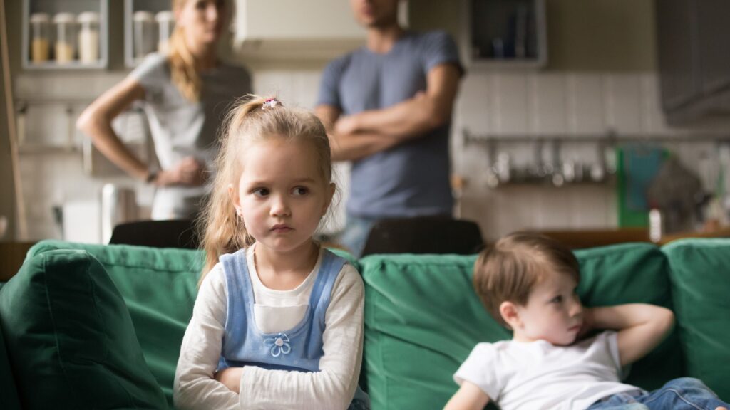 Frustrated kid girl feels upset, offended or bored ignoring avoiding worried parents and brother, little sad sister not talking to child boy after fight sulking sitting on couch, siblings rivalry