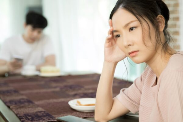 Unhappy woman sitting at dinning table keeping distance from her husband