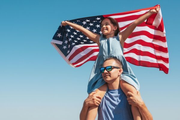 Happy family father and child with usa flag enjoy nature on sky background. Free lifestyle.