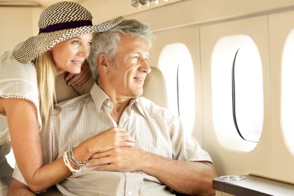 Taking a luxury trip. Smiling senior couple on an airplane looking out the window.