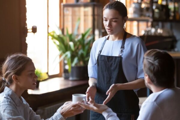 Angry couple client talk dispute with millennial waitress feel dissatisfied with cafe bad service, mad disappointed customers speak with staff complain