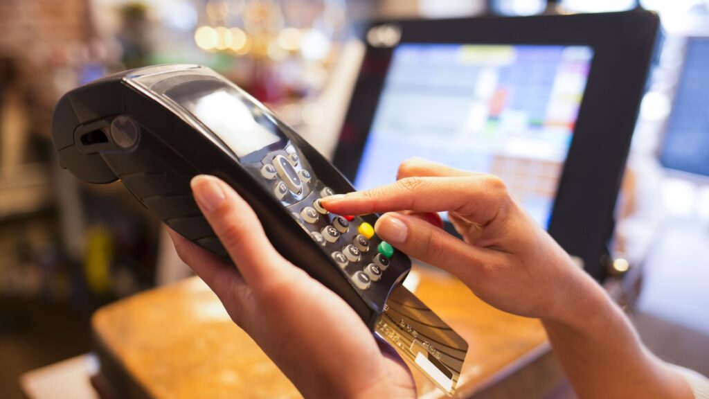 Woman hand with credit card swipe through terminal for sale in restaurant