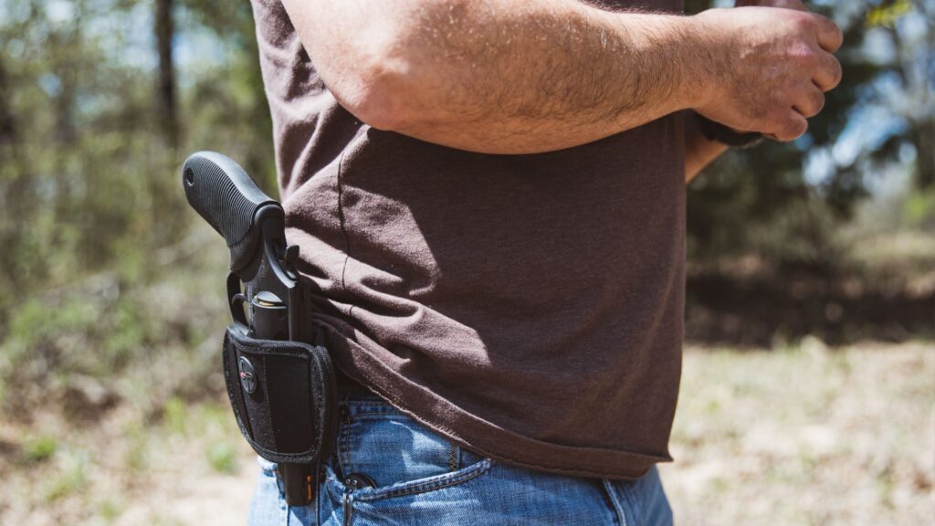 St. Jo, Texas / USA - March 28, 2020: Close up side view of a man wearing an open carry handgun in a holster at his belt outdoors