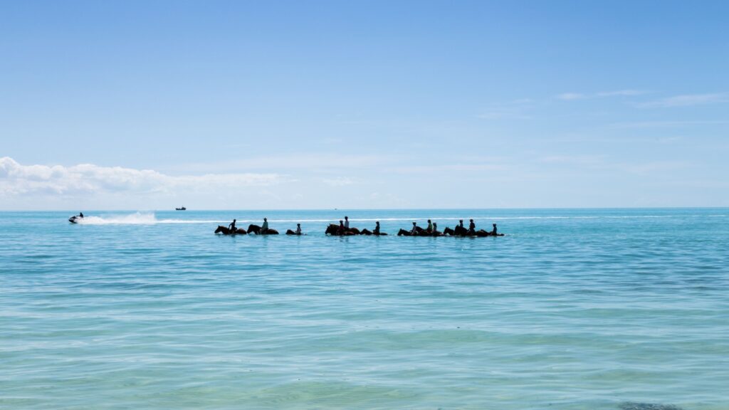 Horseback riding on tropical beach on Turks and Caicos islands.