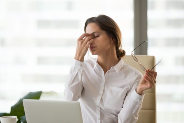 Fatigued businesswoman taking off glasses tired of computer work, exhausted employee suffering from blurry vision symptoms after long laptop use, overworked woman feels eye strain tension problem