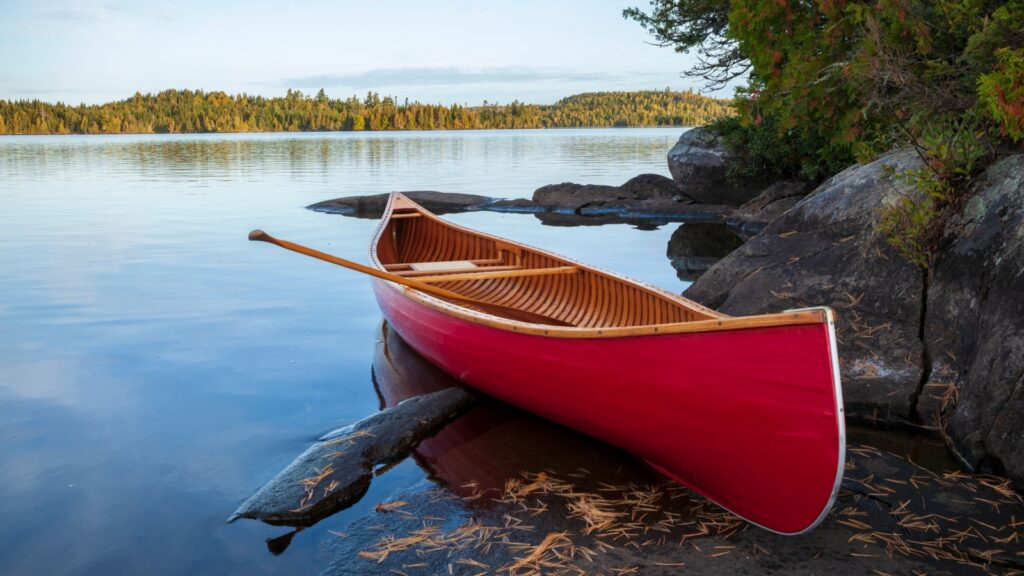 Red wood canoe on rocky shore of a Boundary Waters lake in morning light during autumn