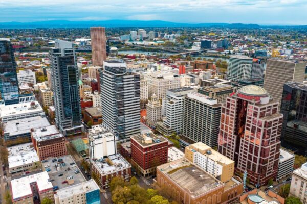 Downtown of Portland, Oregon, the USA with high-rise architecture. Twilight view of the city with mountain silhouettes at backdrop.