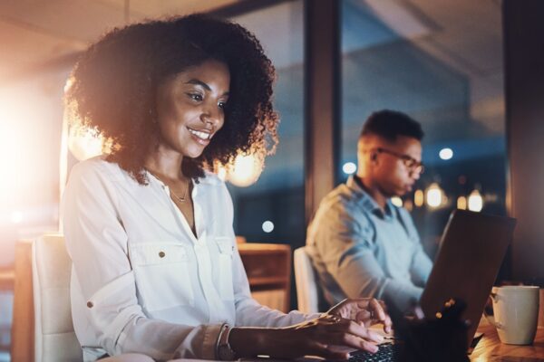 Laptop, night and business woman in office with research for wealth management report with deadline. Computer, typing and African female actuary working overtime on financial investment analysis.