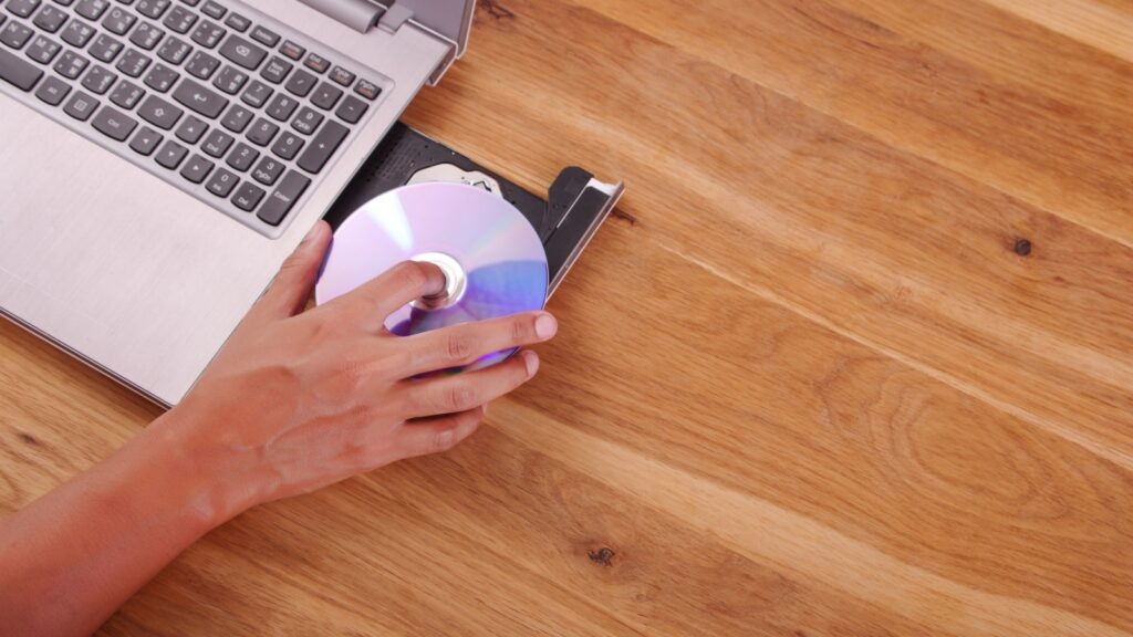 hand holding dvd or cd insert to notebook computer